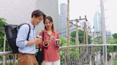 İki genç profesyonel, Bangkok 'ta kahve molasının tadını çıkarıyorlar. Ağır çekimde akıllı telefon kullanıyorlar.