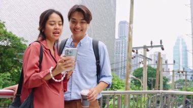 Genç adam ve kadın, muhtemelen iş arkadaşları, ağır çekimde akıllı bir telefona bakarken neşeli bir anın tadını çıkarırlar.