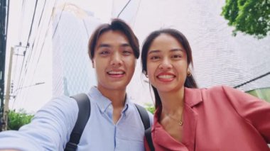 Genç çift, Bangkoks kentsel manzarasının canlı arkaplanına karşı yavaş çekimde selfie çekmekten hoşlanıyor