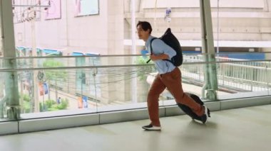 Şehirdeki bir gökdelende aceleyle koşan, tekerlekli bavul taşıyan, Bangkok 'taki kentsel iş hayatını gözler önüne seren bir iş adamı.