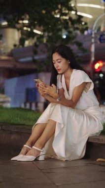 Genç Asyalı iş kadını geceleri Bangkoks 'ta akıllı telefon uygulaması ile meşgul oluyor.