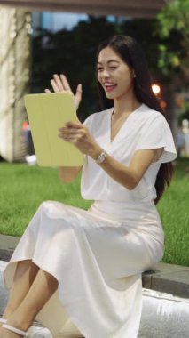 Bangkok 'taki iş kadını geceleri bir parktaki çıkıntıda oturur, tablet üzerinde çalışır ve bir video görüşmesi yapar.