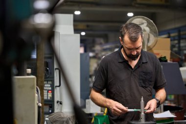 Metal işçisi, bir metalurji fabrikasında özel bir mekanik parçanın ölçümlerini dikkatlice işaretleyerek, hassas üretimi sağlıyordu.