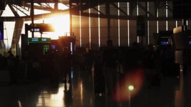Bangkok, Tayland 'daki Suvarnabhumi Havaalanı' nda yürüyen turistler çarpıcı bir günbatımında canlı bir atmosfer yaratıyor.