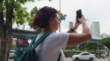 Bangkoks 'un canlı şehirlerinin anılarını yakalayan bir turist, hareketli şehir ortamının ortasında akıllı telefonunu kullanıyor.