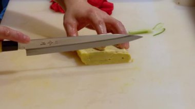 Şef suşi yapmak için Japon usulü tatlı bir omlet olan tamagoyaki dilimliyor.