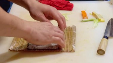 Şef aceleci bir restoranın mutfağında bambu hasırı üzerinde suşi pilavı hazırlar.