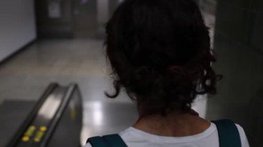 Turist kadın Bangkok metro istasyonunda yürüyor, yürüyen merdivenlere biniyor ve telefonla konuşuyor.