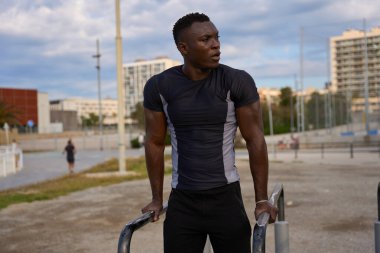 Paralel barlar kullanarak, dalış yaparak, formda kalmaya kendini adamış, konsantre olmuş kas sporcusu.