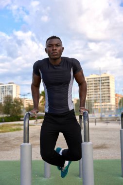 Spor salonunda vücut ağırlığı egzersizi yaparak kaslarını güçlendiren odaklanmış sporcu, sağlıklı yaşam tarzını ve kentsel fitness 'i teşvik ediyor.