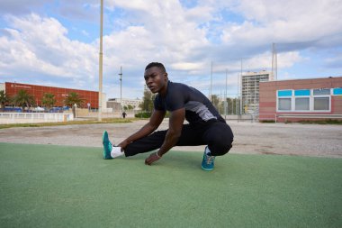 Kentsel çevrede spor yaptıktan sonra bacakları esneten atletik erkek sağlıklı yaşam tarzı ve uygunluğu teşvik ediyor.