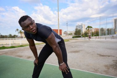 Afrika kökenli Amerikalı sporcu şehir parkında yoğun bir jimnastik çalışmasından sonra dinleniyor.