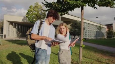 İki üniversite öğrencisi, güneşli bir günde okul ödevlerini tartışıp fikir alışverişinde bulunuyorlar.