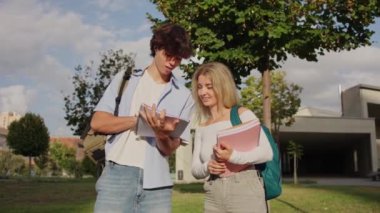 İki üniversite öğrencisi kampüste dijital tablet ve ders kitapları kullanarak bir proje üzerinde çalışıyorlar.