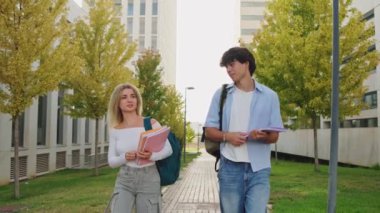İki üniversite öğrencisi, sonbahar renkleriyle dolu canlı bir kampüste birlikte yürürken keyifli bir sohbetin tadını çıkarıyor.