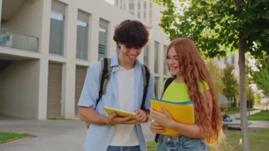 İki üniversite öğrencisi, bilgi paylaşmak için bir tablet kullanarak çalışmalarını tartışıyor ve işbirliği yapıyorlar.