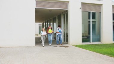 Üç mutlu öğrenci üniversitelerindeki sınavların bitişini kutlarken gazetelerini havaya fırlatıyorlar.