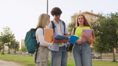 Üç üniversite öğrencisi kampüste durmuş notları hakkında hararetli bir tartışma yapıyorlar.