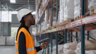 Depo işçisi, ağır çekimde raflarda paketleri tarıyor ve verimli envanter yönetimi gösteriyor.