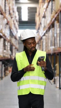 Yüksek görüş mesafesinde bir depo çalışanı, ağır çekimde barkod tarayıcısı kullanarak envanteri tarıyor.