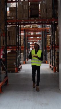 Depo çalışanı bir tablet kullanıyor ve yavaş çekimde envanteri kontrol ediyor.