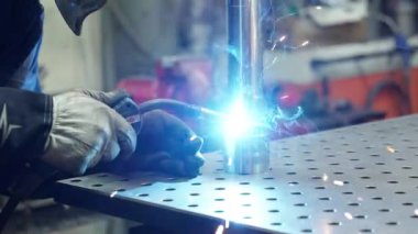 Kaynakçı dikkatli bir şekilde metal parçaları birleştirir, parlak kıvılcımlar yaratır ve büyüleyici bir işçilik gösterisi yapar.