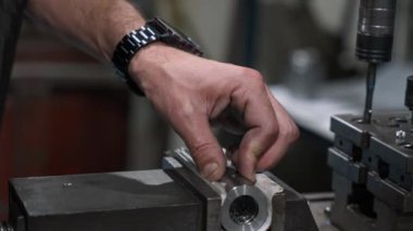 Makinist bir atölyede metal bir parça hazırlarken üretim ve üretim amaçları için hassas bir delik açıyor