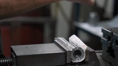 Makinist, üretim sürecinde hassasiyet ve kaliteyi sağlamak amacıyla bir atölyede sondaj için metal bir parça hazırlıyor.