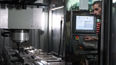 Bir fabrika ortamında bir cnc değirmen makinesini programlayan mühendis, metal işleme ve üretim süreçlerinde hassasiyet gösteriyor