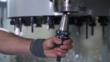 Makinist endüstriyel tornada matkap ucunu değiştiriyor, metal üretiminde hassasiyet ve beceri sergiliyor.