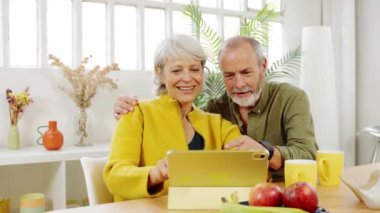 Mutlu olgun çift, mutfak masalarında birlikte tablet kullanırken birbirlerine eşlik etmekten zevk alır.