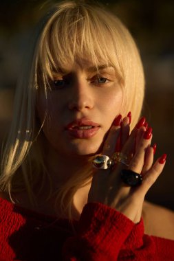 Sarışın Ukraynalı model şık yüzükler ve kırmızı tırnaklar sergiliyor. Moda fotoshoot sırasında, özgüven ve zarafet saçıyor.