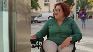 Tekerlekli sandalye kullanan bir kadın, asansör düğmesine basarak ulaşabilirlik altyapısını gösteriyor.