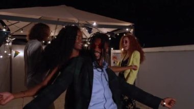 Cok uluslu arkadaslar neşe ve baglanti dolu bir gecede birlikte gülüp dans ediyorlar.