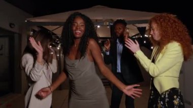 Dört arkadaş dans ediyor ve neşe dolu bir çatı partisinde eğleniyorlar. Kahkaha, müzik ve canlı şehir ışıklarıyla.