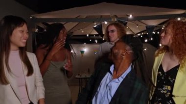 Genç yetişkinler canlı bir çatıda dans edip gülüyorlar. Müzik ve kutlamalarla dolu canlı bir gecenin tadını çıkarıyorlar.