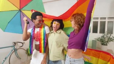 Lgbtq arkadaşları sevinçle gururu kutluyorlar, gökkuşağı bayrağı sallıyorlar ve renkli bir şemsiye sallıyorlar.