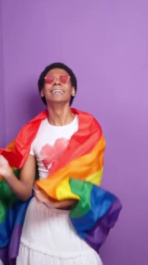 Yavaş çekim, mor bir arkaplana karşı canlı bir lgbt gurur bayrağı sallayan ikili olmayan genç bir modeli yakalar.