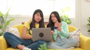 İki arkadaş, bilgisayar ve kredi kartı kullanarak rahat bir koltukta başarılı bir alışveriş yapmayı seviyor.