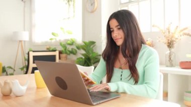 Laptop ve akıllı telefon kullanan, işini ve finansmanını idare eden genç bir kadın.