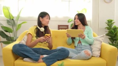 İki arkadaş rahat bir kanepede birlikte vakit geçirir, dijital tablette içeriklerini paylaşır ve sohbet ederler.