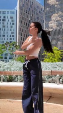 Yetenekli dansçı, şehir arka planına karşı dinamik bir açık hava gösterisinde akışkan hareketler sergiliyor