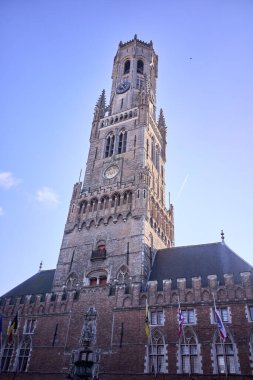 Bereketli mavi gökyüzüne karşı yükselen ve Belçika 'nın karmaşık gotik mimarisini ve tarihsel önemini vurgulayan görkemli bir çan kulesi.