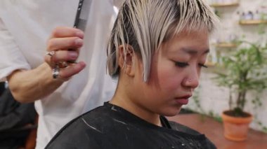 Yetenekli bir kuaför, bir kadının saçını dikkatlice şık bir Bob 'a dönüştürür. Yavaş çekim, canlı bir salon ortamında hassasiyet ve yaratıcılığı yakalar.
