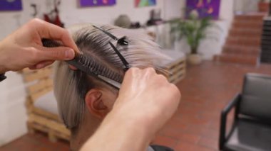 Profesyonel kuaför kadın saçlarını dikkatlice kesiyor keskin makas ve hassas stil tekniklerini yavaş çekimde kullanıyor.