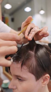 Modern bir kuaförde makas ve tarak kullanarak kusursuz saç kesimi yapan yetenekli bir kuaför. Yakından bakıldığında teknik ve uzmanlık odaklı