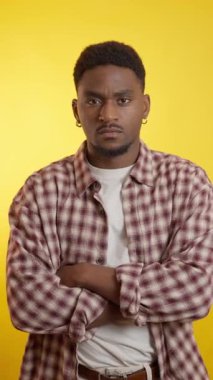 Afrikalı Amerikalı genç bir adamın canlı sarı bir arka planda farklı yüz ifadeleri ve jestleri gösteren bir stüdyo fotoğrafı.