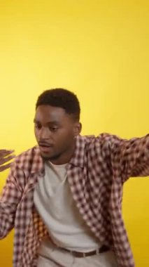 Genç ve şık erkek dansçı, modern hip hop ritmini ifade ederek, canlı sarı arka planda tutku ve enerjiyle dinamik serbest stil hareketleri sergiliyor.