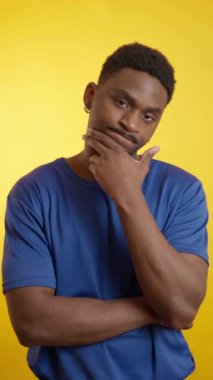 Etkileyici Afrikalı Amerikalı genç yetişkin dinamik duygu çeşitliliği sergiliyor, parlak sarı arka plana karşı nüanslı yüz reaksiyonlarıyla karmaşık psikolojik durumları aktarıyor.