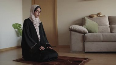 Kadın, dingin bir oturma odasındaki paspas üzerinde meditasyon yapıyor, sükuneti ve sükuneti ağır çekimde somutlaştırıyor.
